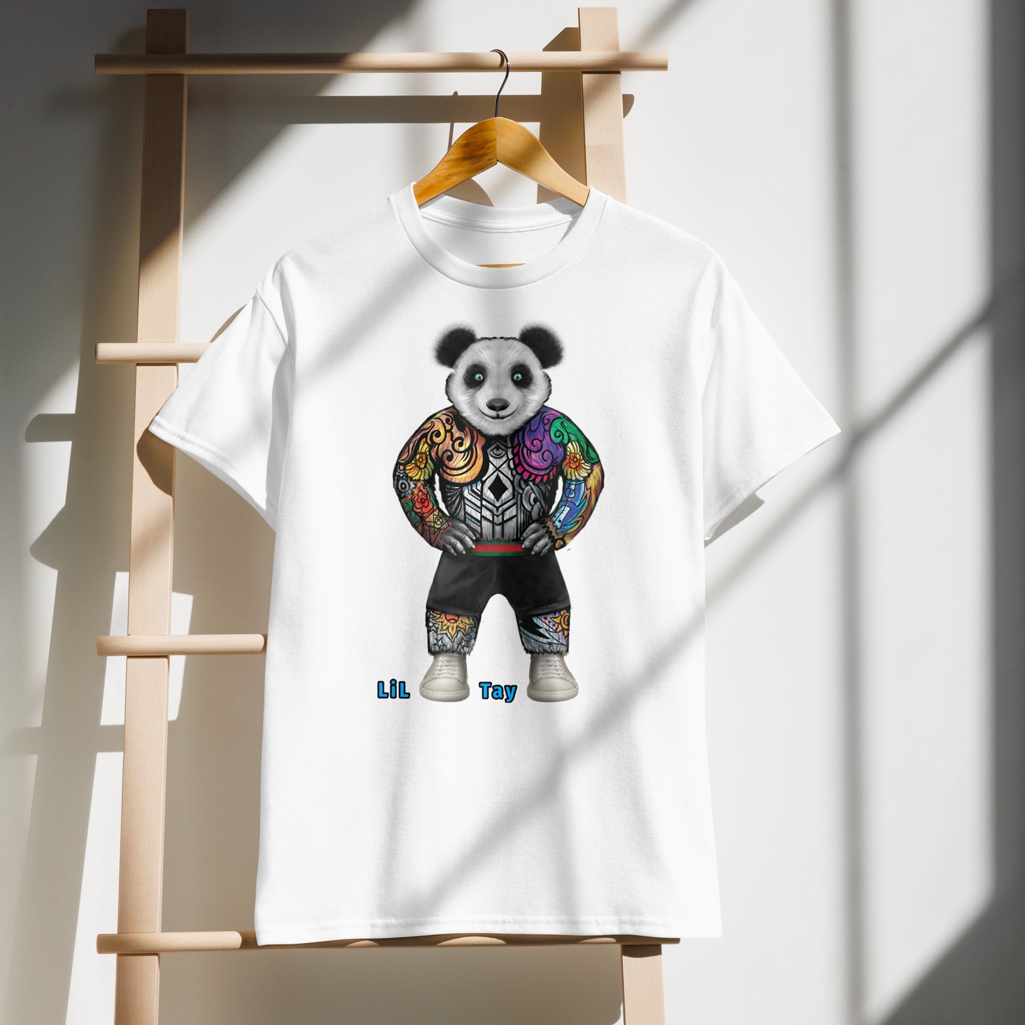 White t-shirt with a colorful panda design hanging on a wooden rack.